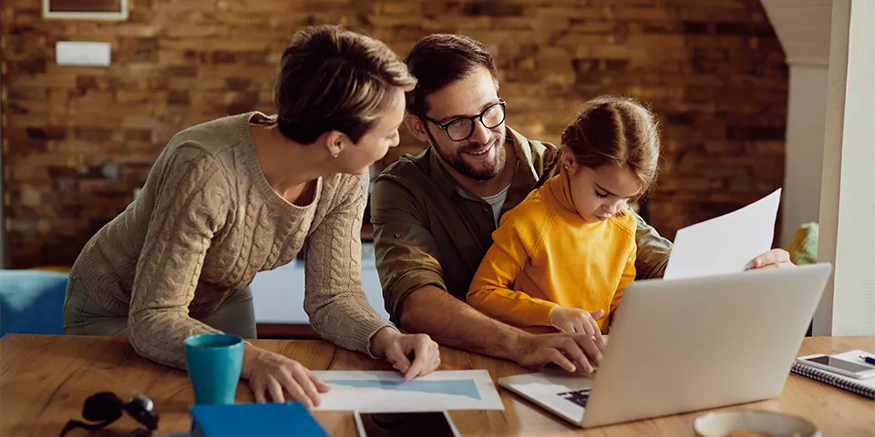 family sitting together with parents looking at a laptop