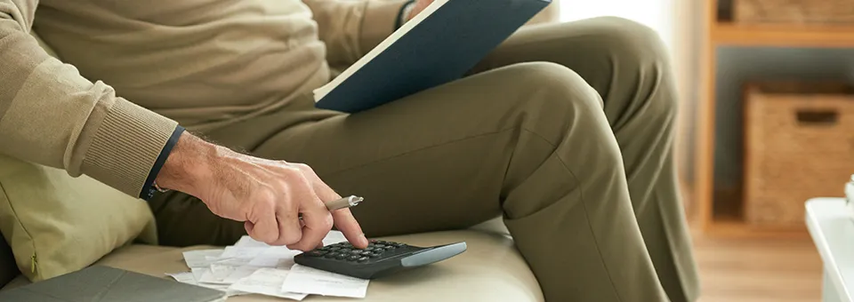man sitting on a couch with notebook and calculator