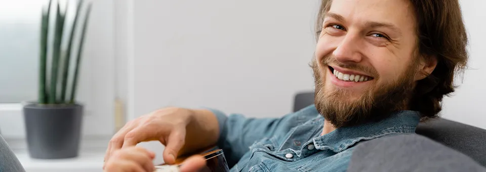 relaxed man laying on the couch and playing guitar