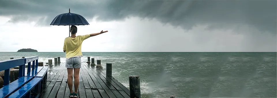 woman standing at the pier under an umbrella on a dark moody day